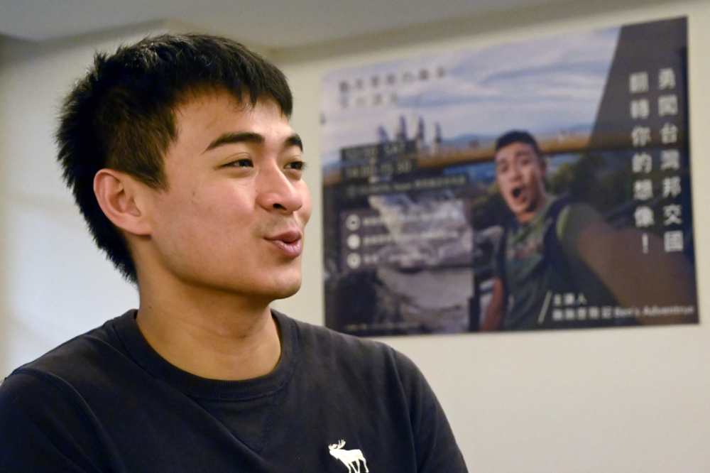 This picture taken on February 13, 2019 shows Taiwanese YouTuber Ben Wu speaking in front of a poster of himself during his travels during an interview in Taipei. AFP / Sam Yeh 