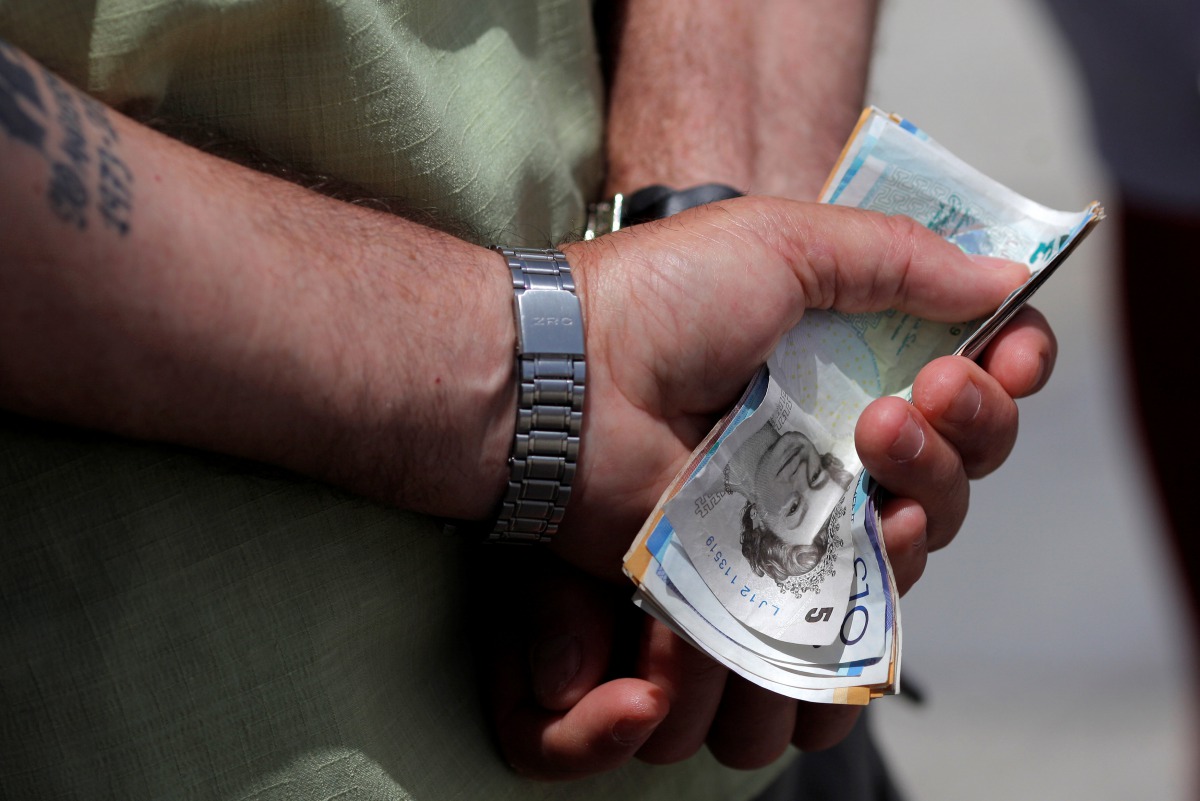 A man holds various English Pound notes as he waits in line to exchange it for Euros notes outside a money exchange office in the British overseas territory of Gibraltar, June 24, 2016. (AFP) 