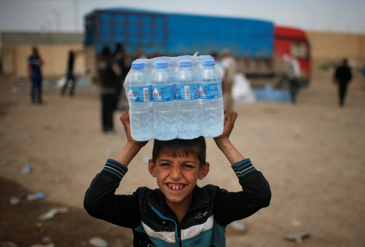 A displaced Iraqi boy smiles after receiving water in western Mosul, Iraq, March 28, 2017. Reuters/Suhaib Salem