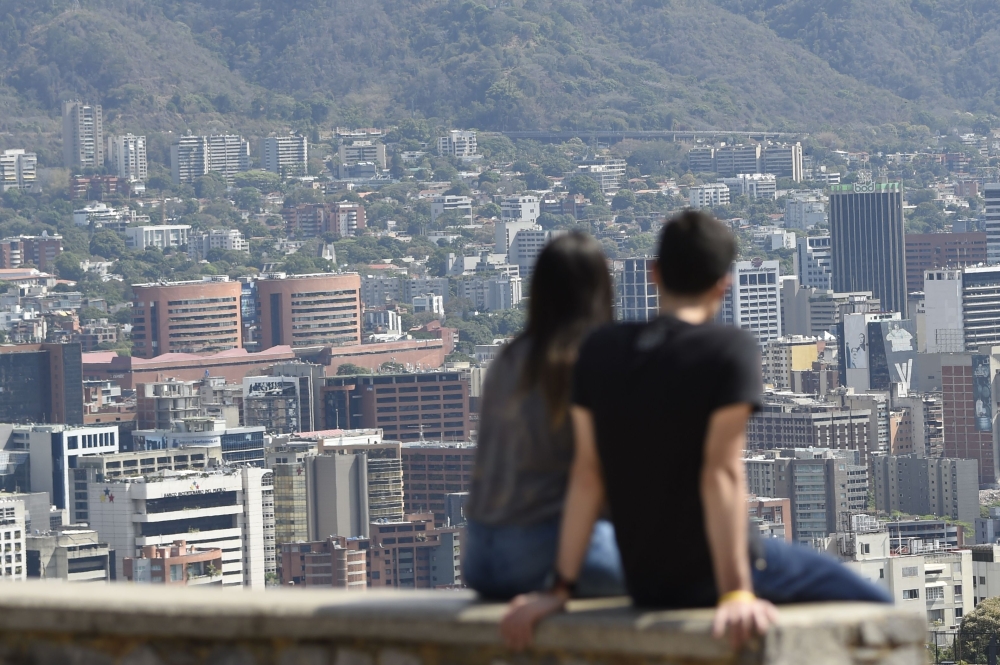 A couple sits and looks at Caracas on March 12, 2019 as a nationwide power blackout entered its fifth day.  AFP / Juan Barreto 