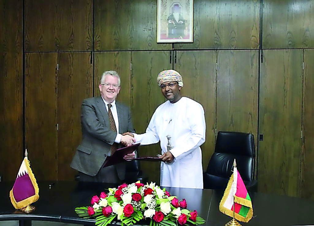 Michael Ryan, Chief Executive Officer of the QFC Regulatory Authority (left), and Taher Salim Al Amri, Executive President of the Central Bank of Oman, exchanging documents after the signing ceremony.