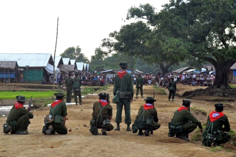 Myanmar personnel stand guard while a mob looks on following unrest at an Internally Displaced People camp for Muslim Rohingyas on the outskirts of Sittwe town in Rakhine State on August 9, 2013. (AFP) 