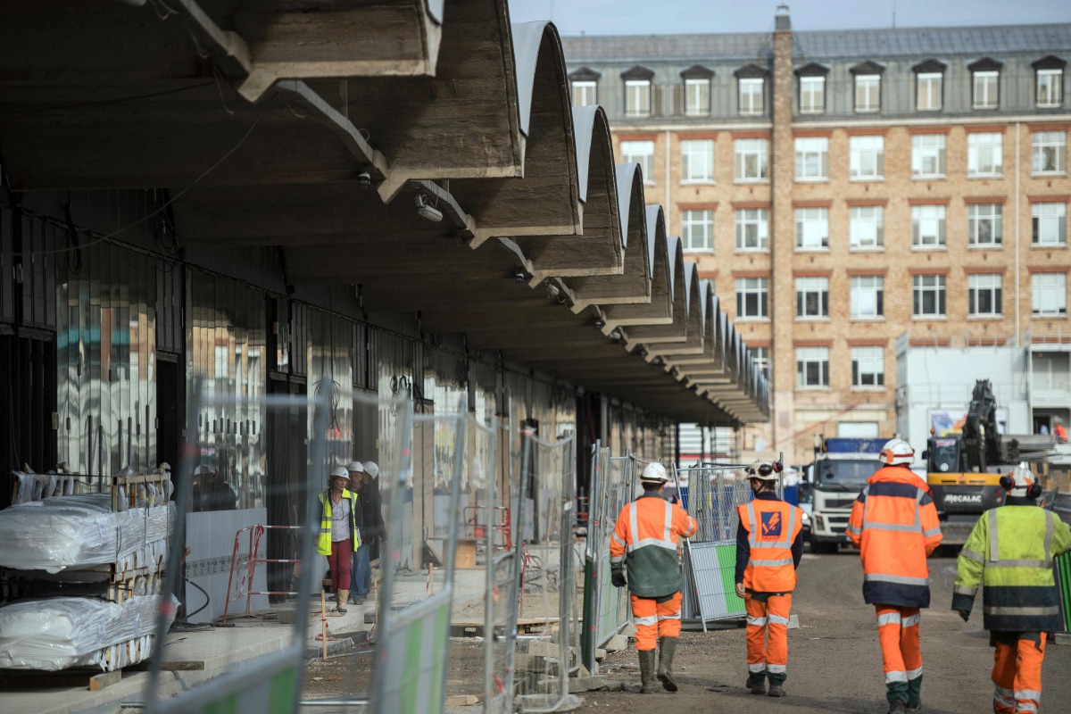 This file photo taken on October 18, 2016 shows workers walking through the construction site of the world-biggest start-up incubator Station F, formerly known as the Halle Freyssinet in Paris. AFP/Lionel Bonav