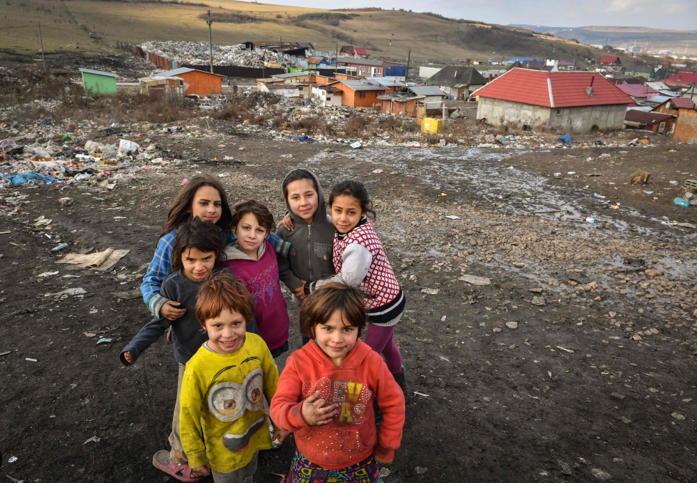 Children pose in front of makeshift shacks where they live with their families on the edge of the Pata-Rat landfill site next to Cluj-Napoca city on February 7, 2019. AFP/Daniel Mihailescu