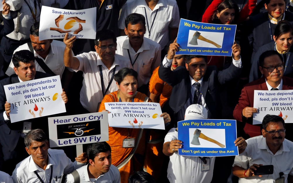 Jet Airways employees hold placards and banners during a protest demanding to 