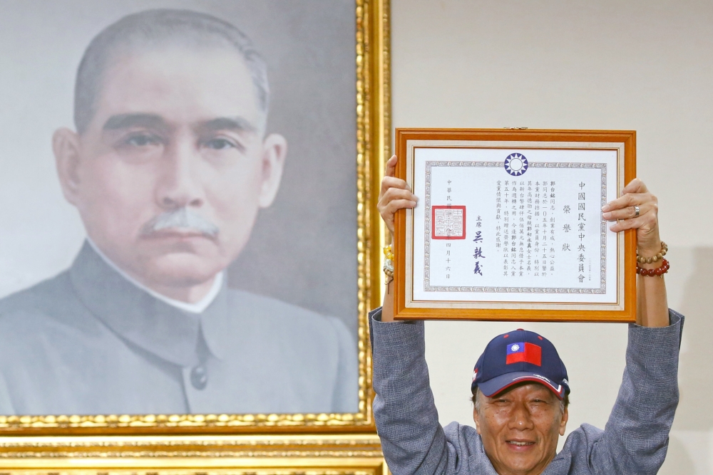 Terry Gou, founder and chairman of Foxconn, holds a testimonial next to a portrait of Sun Yat-sen, the founding father of Taiwan, as he announces seeking the nomination of Taiwan's opposition Kuomintang party to run for the island's presidency, in Taipei,