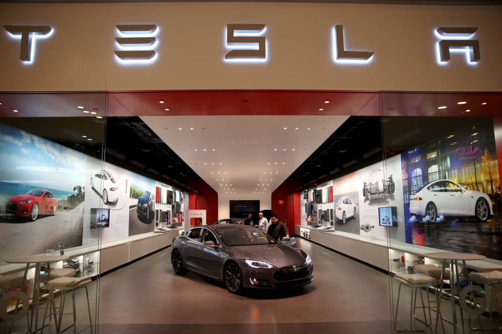 In this file photo taken on February 19, 2014 people look at a Tesla Motors vehicle on the showroom floor at the Dadeland Mall in Miami. AFP/Getty Images North America/Joe Raedle