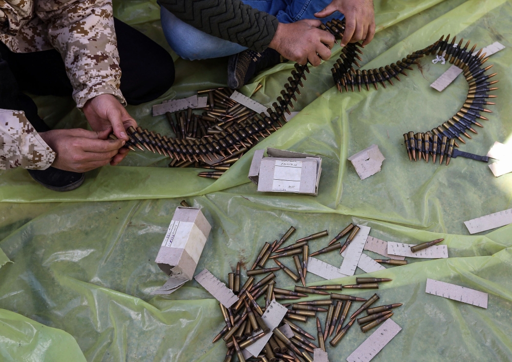 Men load ammunition belts at a position held by forces of Government of National Accord in the suburb of Wadi Rabie about 30 kilometres south of Tripoli, Libya on April 12, 2019. AFP/Mahmud Turkia