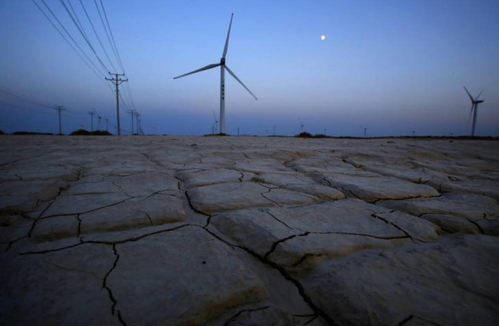 Cracked earth marks a dried-up area near a wind turbine used to generate electricity at a wind farm in Guazhou, 950km (590 miles) northwest of Lanzhou, Gansu Province September 15, 2013. Reuters/Carlos Barria