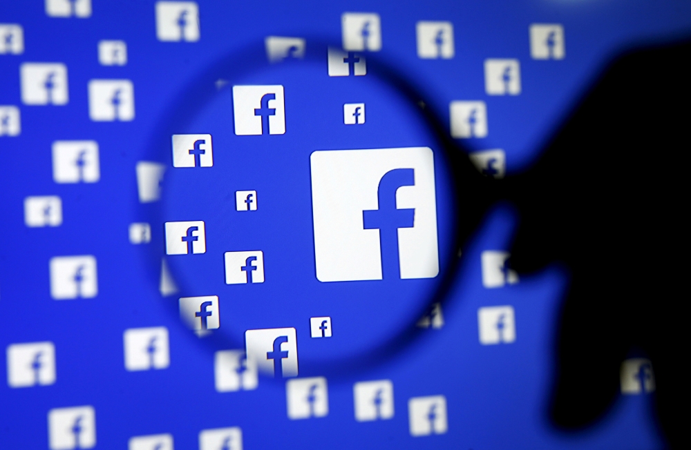 FILE PHOTO: A man poses with a magnifier in front of a Facebook logo on display in this illustration taken in Sarajevo, Bosnia and Herzegovina, December 16, 2015. REUTERS/Dado Ruvic/Illustration