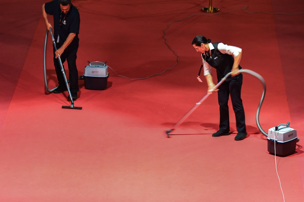 Employees vaccum the red carpet after guests and film cast and crews arrived for the screening of the film 