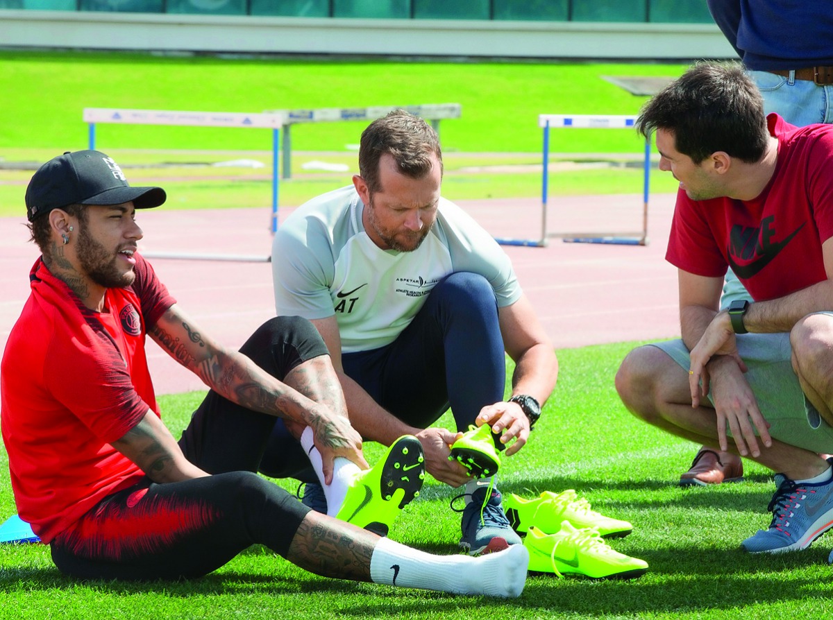 Neymar (left) is assisted by Aspetar experts as he checks a shoe model in this file picture.