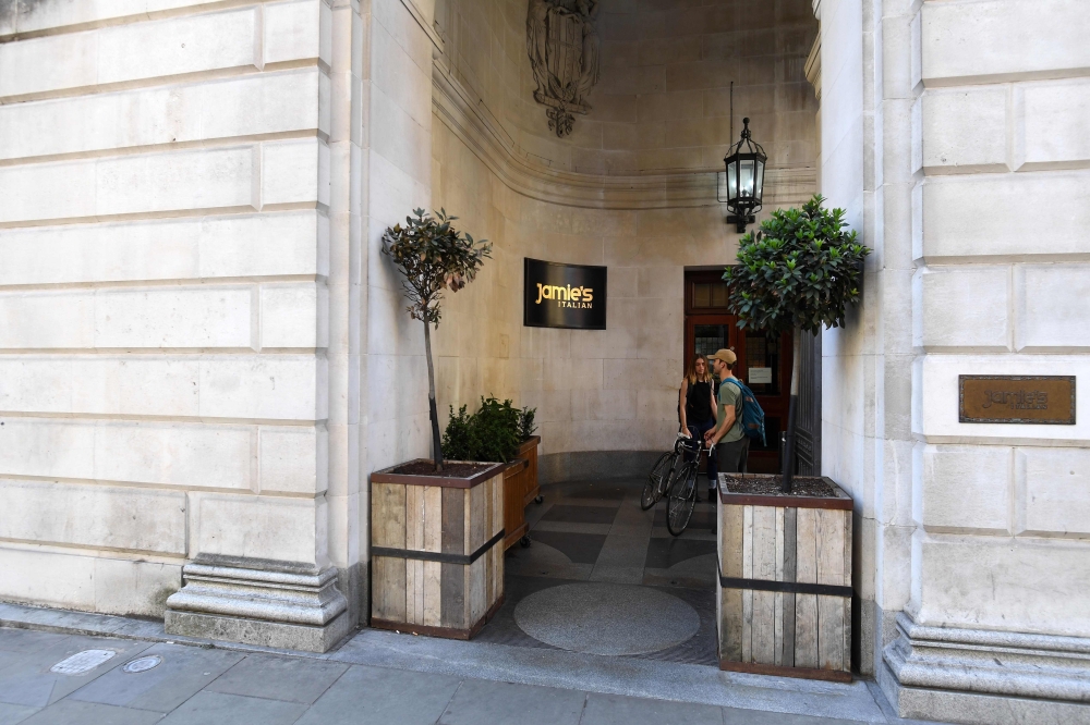Pedestrians stand outside the locked doors of a closed-down Jamie's Italian restaurant in Manchester, northern England on May 21, 2019. AFP / Paul Ellis 