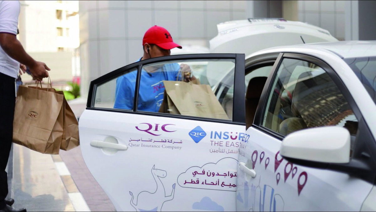Volunteers from Qatar Insurance distributing Iftar meals by roadside. 