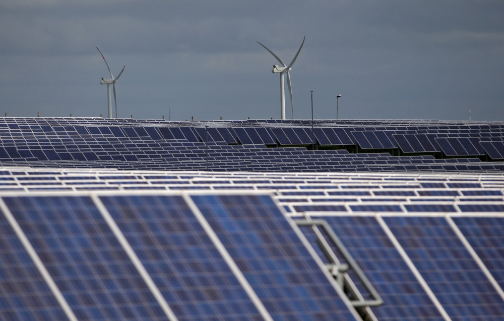 A solar power plant is seen past wind turbines in Canino, central Italy, April 27, 2016. Reuters/Max Rossi