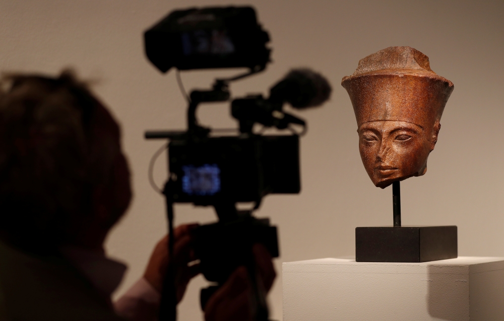 A cameraman films an Egyptian brown quartzite head of the God Amen which will be sold at auction at Christie's in London, Britain, July 4, 2019. Reuters/Peter Nicholls