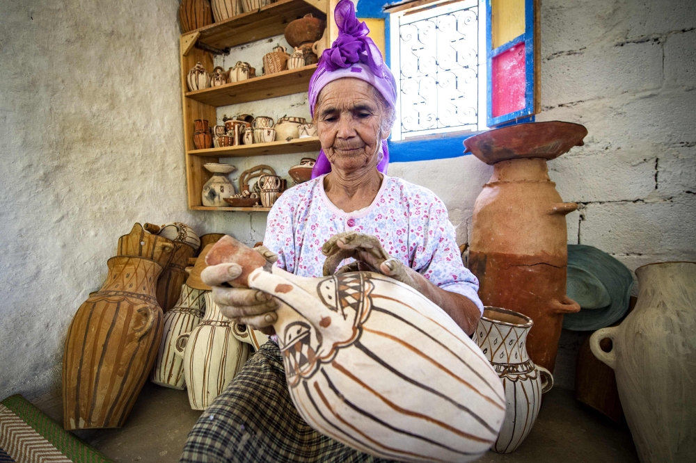 Moroccan potter Aicha Tabiz, also known as Mama Aicha, holds one of her works near the village of Ourtzagh in the foothills of the Rif mountains on June 12, 2019. AFP / FADEL SENNA