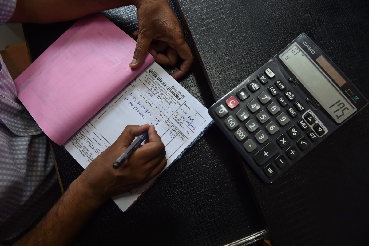 An Indian shopkeeper prepares a bill for a customer at his shop in New Delhi on August 3, 2016. AFP Sajjad Hussain 
