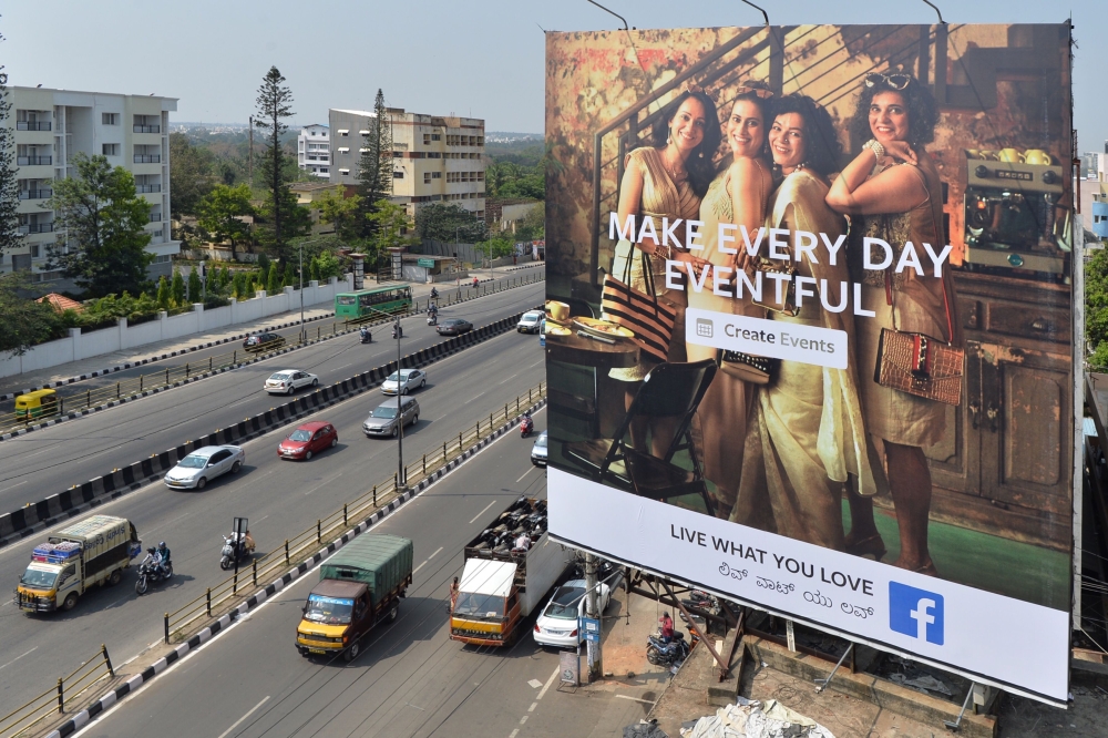 Indian commuters pass a poster advertising ‘Facebook Live What You Love’ campaign in Bangalore on March 22, 2018. AFP/Manjunath Kiran