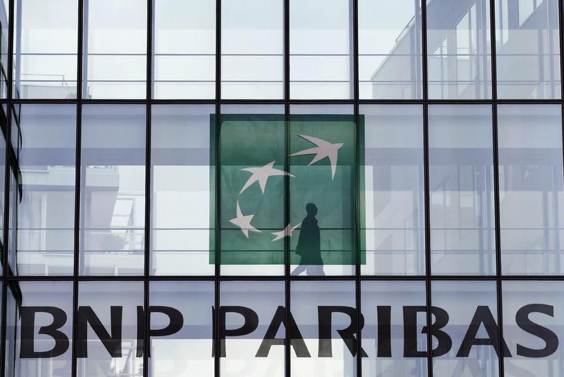 An employee walks behind the logo of BNP Paribas in a company's building in Issy-les-Moulineaux, near Paris, June 2, 2014. Reuters/Charles Platiau 