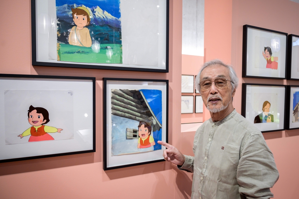 Japanese animator and character designer Yoichi Kotabe poses next to cartoon boards from the Japanese animated series 
