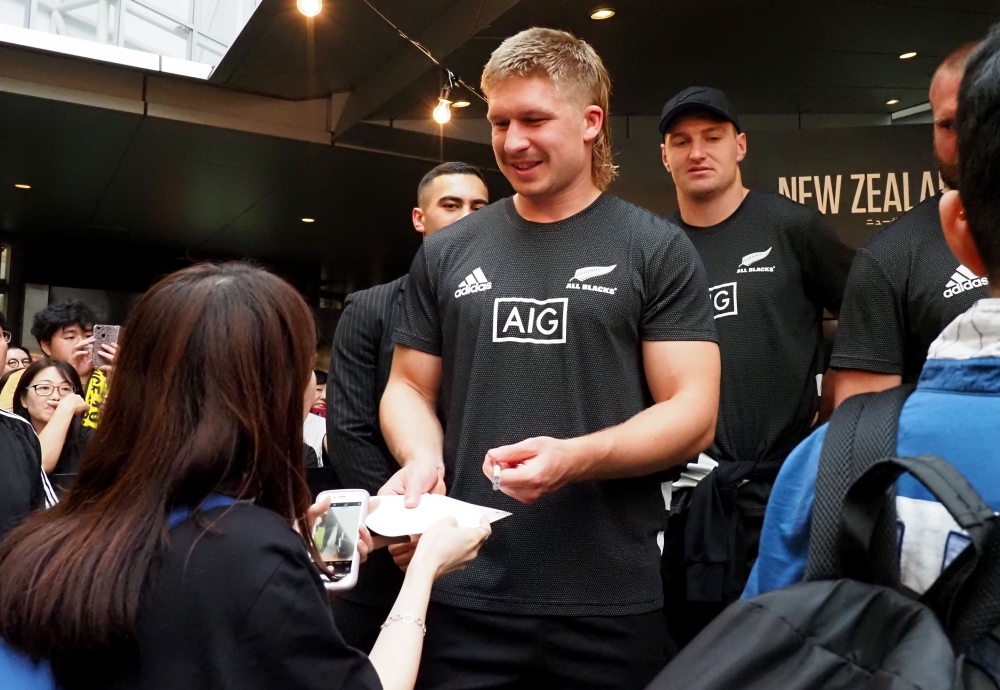 (FILES) In this file photo taken on September 22, 2019, New Zealand's All Blacks player Jack Goodhue (C) signs his autograph during a promotional event by tourism New Zealand in Tokyo, during the Japan 2019 Rugby World Cup. AFP / Toshifumi KITAMURA / 