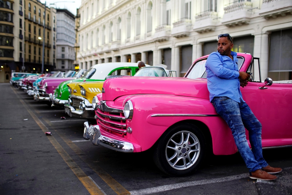 Giovani Bernati, a driver  waits for tourists beside vintage cars used as taxi in Havana, Cuba, October 5, 2018. Reuters / Alexandre Meneghini