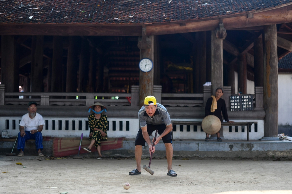 This photograph taken on October 6, 2019 shows an elderly man playing croquet in a courtyard in Hanoi's Soc Son district. AFP / Manan VATSYAYANA