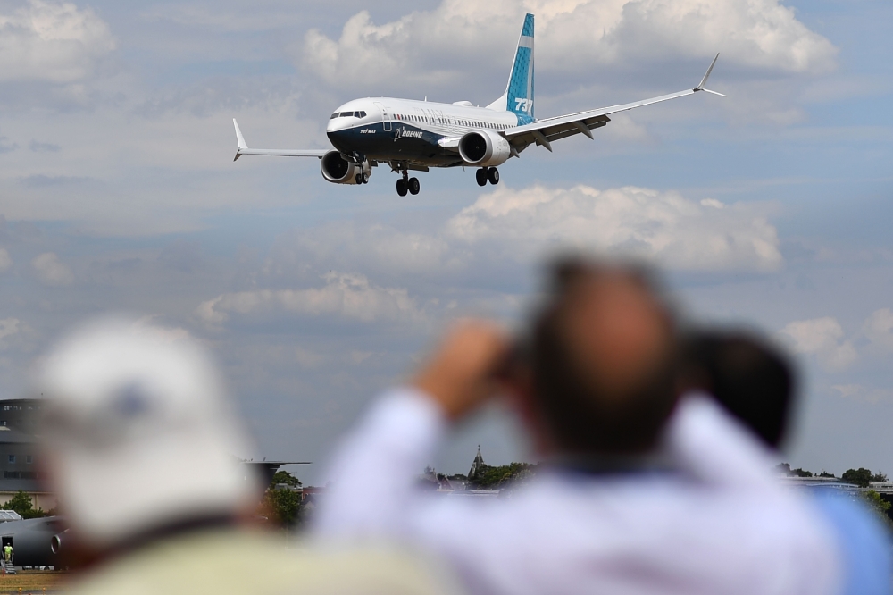 Visitors watch as a Boeing 737 Max lands after an air display during the Farnborough Airshow south west of London on July 16, 2018. AFP / Ben Stansall
