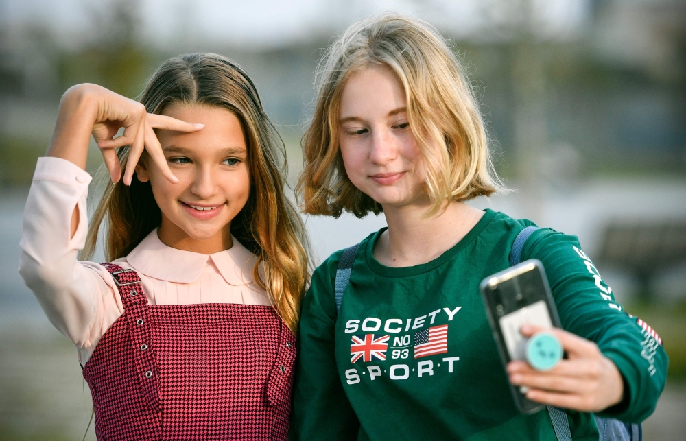 Russian child blogger Liza Anokhina (L), 12, participates in a shoot for her blog in a Moscow park on September 13, 2019. AFP / Alexander Nemenov 
