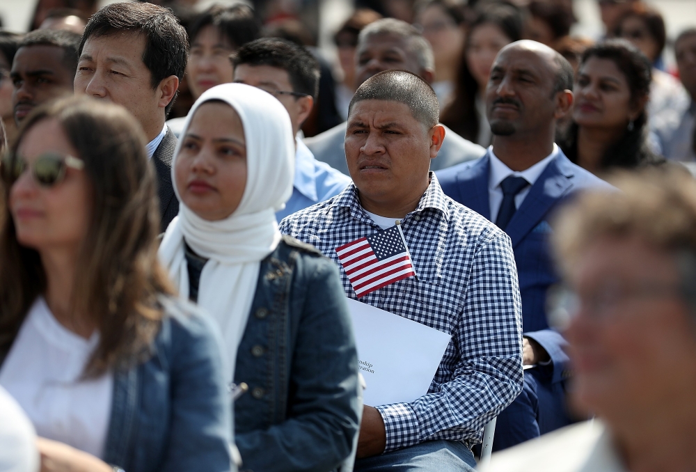 Immigrants look on before being sworn in as American citizens during a naturalization ceremony on the flight deck of the USS Hornet on July 3, 2018 in Alameda, California. Justin Sullivan / Getty Images / AFP