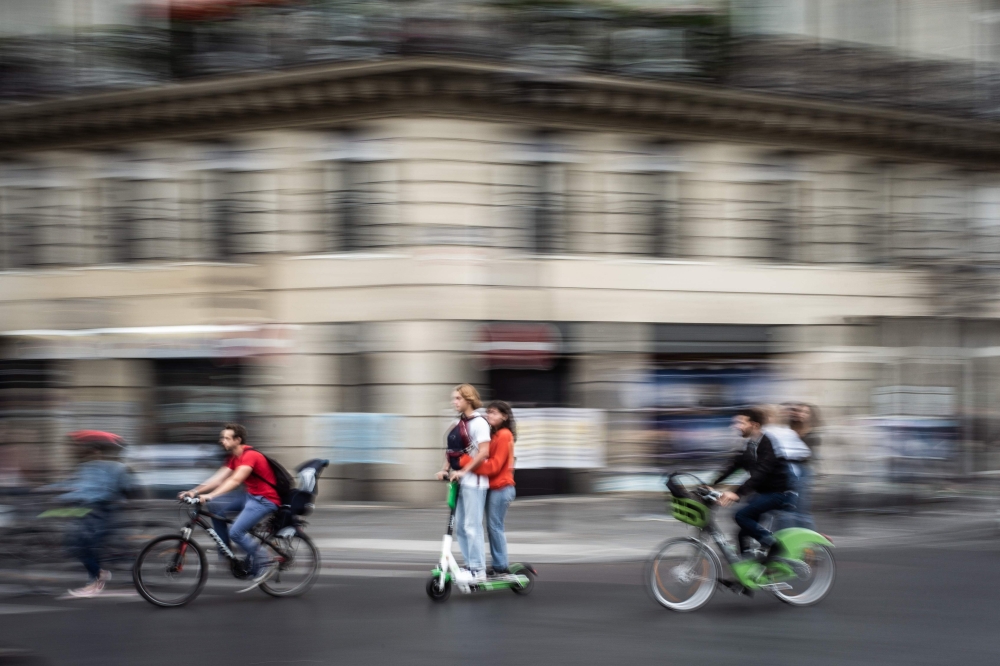 In this file photo taken on September 13, 2019 a couple rides an electric scooter in Paris. (AFP / Martin Bureau) 