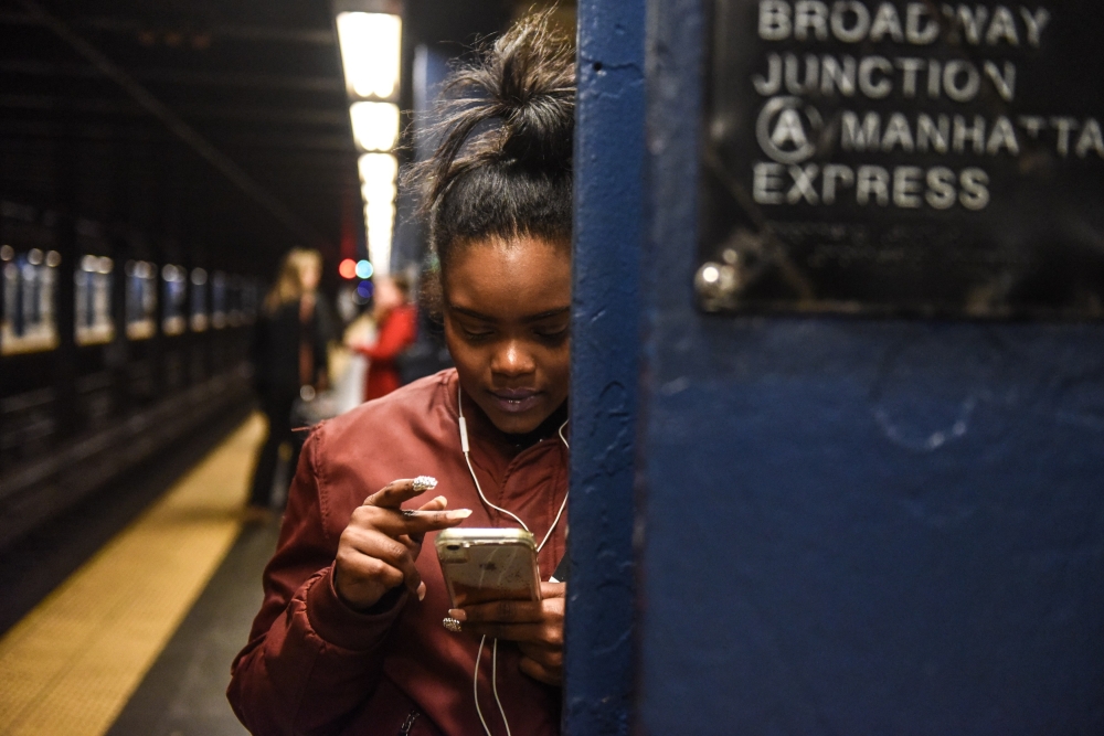  A woman looks at her phone while waiting on the platform at the Broadway Junction subway station on November 14, 2019 in New York City.  Stephanie Keith/Getty Images/AFP