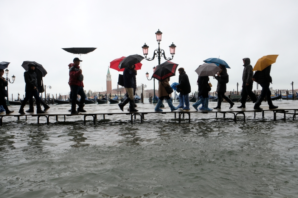 People walk on a catwalk in the flooded St Mark Square during a period of seasonal high water in Venice, Italy November 12, 2019. Reuters / Manuel Silvestri