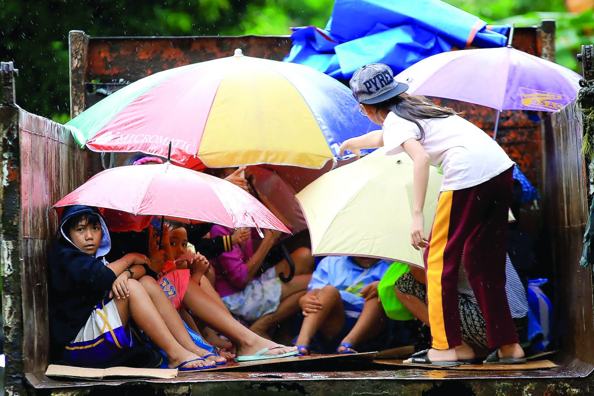 Youngsters sit in a truck after the local government implemented preemptive evacuations at Barangay Matnog Daraga Albay province on December 25, 2016 due to the approaching typhoon Nock-Ten (AFP) 