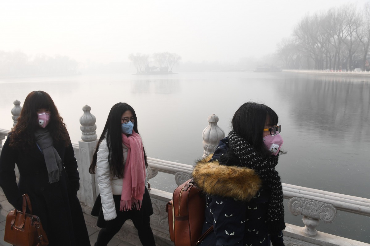 Chinese women wear masks on a heavily polluted day in Beijing on January 1, 2017. AFP / Greg Baker