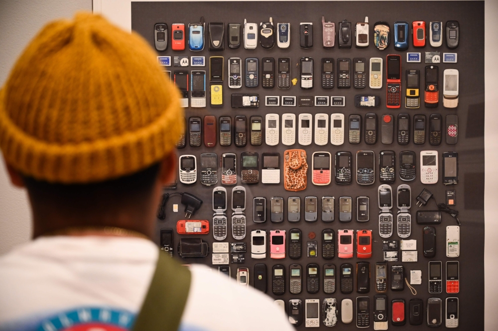A visitor looks at a photo of cell phones confiscated from migrants at the exhibition 