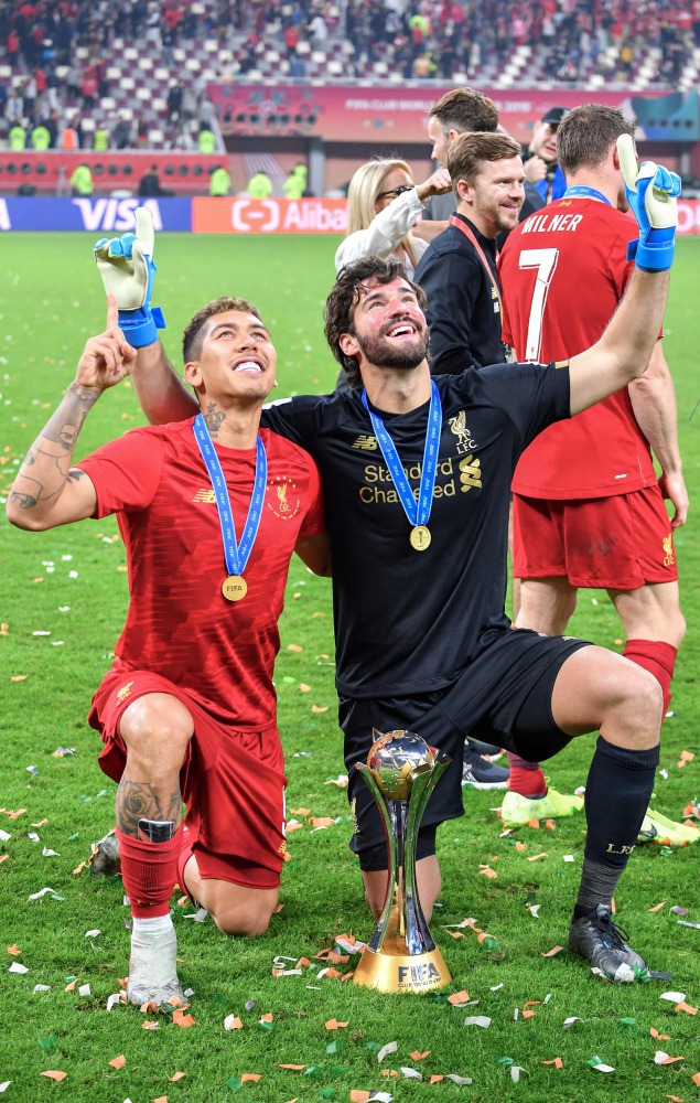 Liverpool’s Brazilian midfielder Roberto Firmino (left) and goalkeeper Alisson Becker pose with the trophy.
