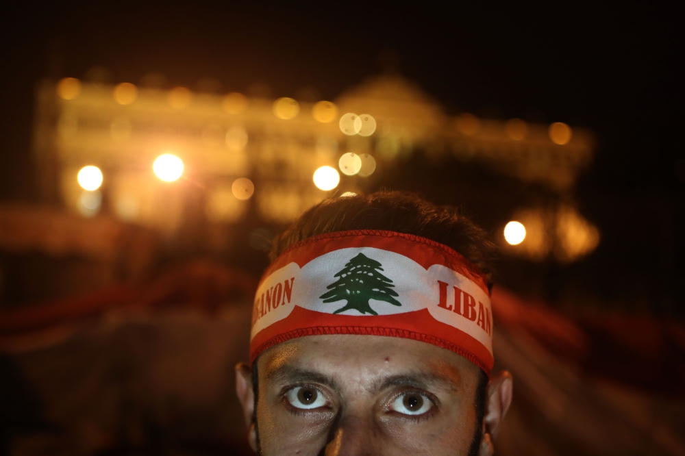 A Lebanese anti-corruption protester, his forehead wrapped with the national flag, poses in front of the Grand Serail (government building) during a protest in downtown Beirut on December 22, 2019.  AFP / PATRICK BAZ