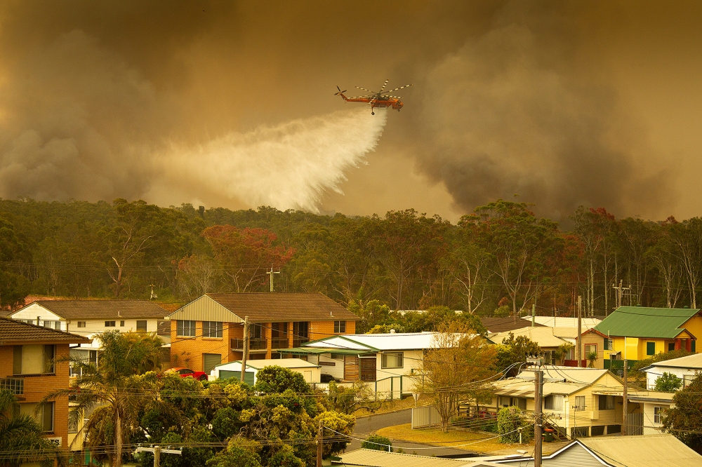 FILE PHOTO: An Air-crane water bombing helicopter drops water on a bushfire in Harrington, Australia, November 8, 2019. AAP Image / Shane Chalker via Reuters