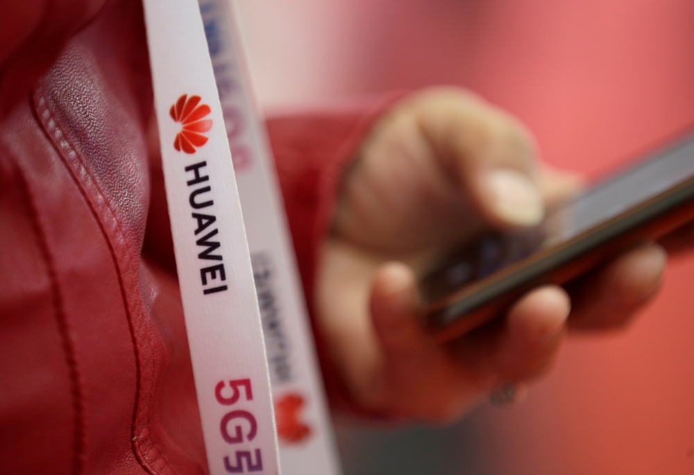 FILE PHOTO: An attendee wears a badge strip with the logo of Huawei and a sign for 5G at the World 5G Exhibition in Beijing, China November 22, 2019. REUTERS/Jason Lee