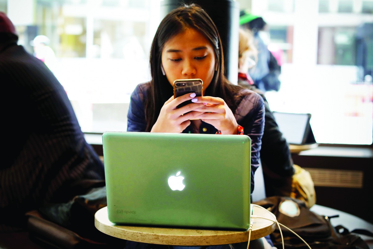 A woman uses her Apple iPhone and laptop in a cafe in lower Manhattan in New York City, US, May 8, 2019. Reuters/Mike Segar
