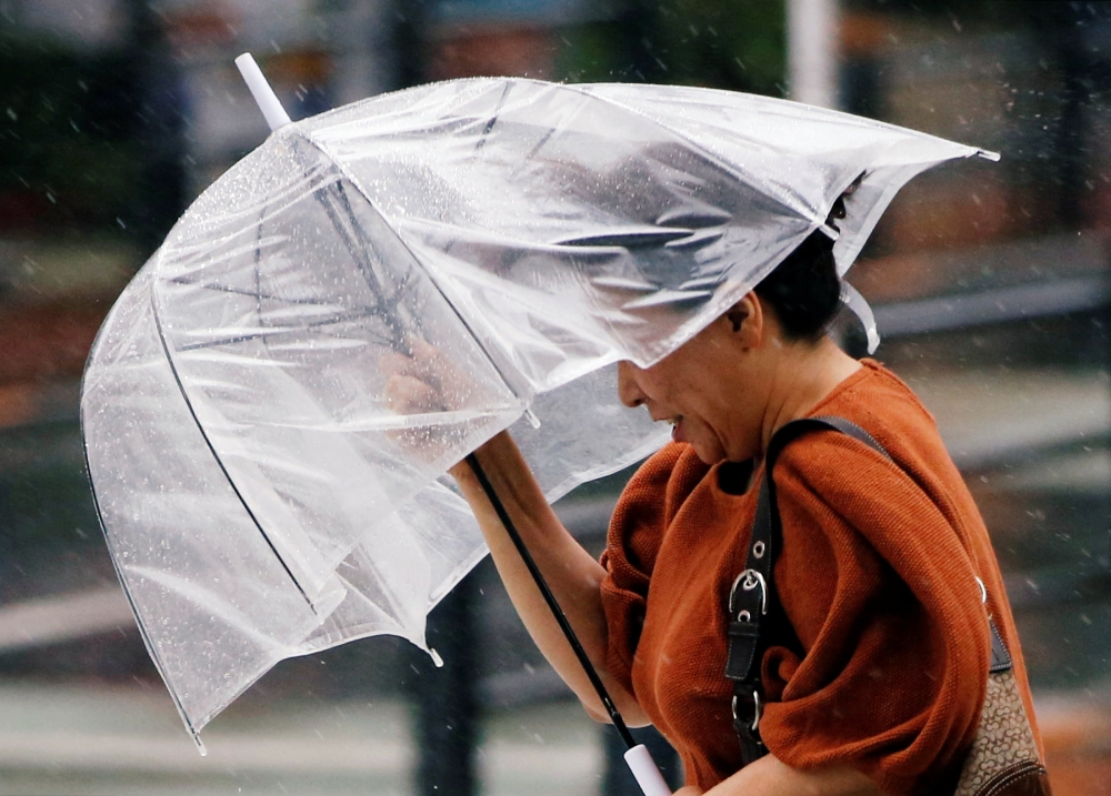 A passerby, using an umbrella, struggles against a heavy rain and wind in Tokyo, Japan, July 28, 2018. Reuters / Issei Kato