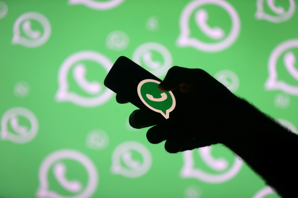 A man poses with a smartphone in front of displayed Whatsapp logo in this illustration dated September 14, 2017. Reuters / Dado Ruvic