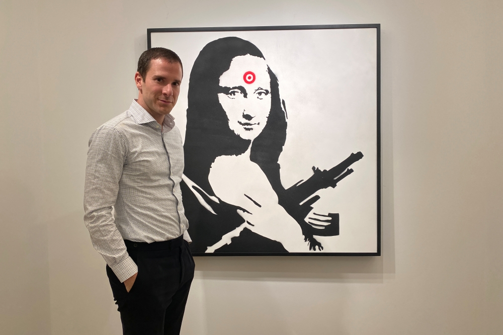 Scott Lynn, CEO and founder of Masterworks, poses next to a Banksy artwork in New York, U.S., February 11, 2020. Picture taken February 11, 2020. REUTERS/Aleksandra Michalska 