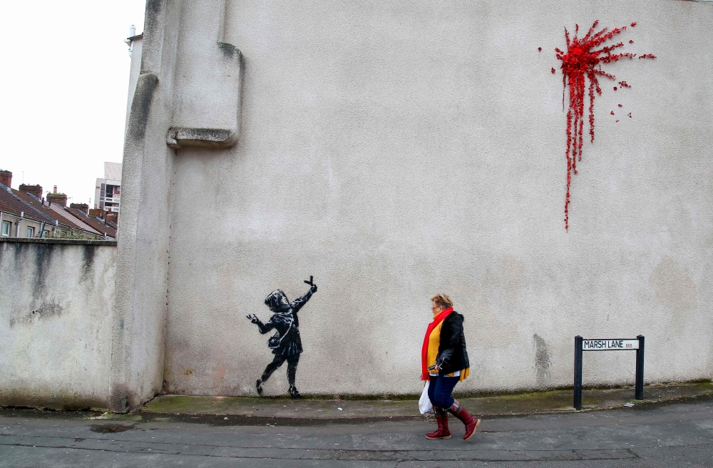 A piece of street art showing the stencilled image of a young girl firing a slingshot of flowers and leaves and confirmed, on his official social media accounts, by elusive artist Banksy as his work is pictured on the wall of a building in Bristol on Febr