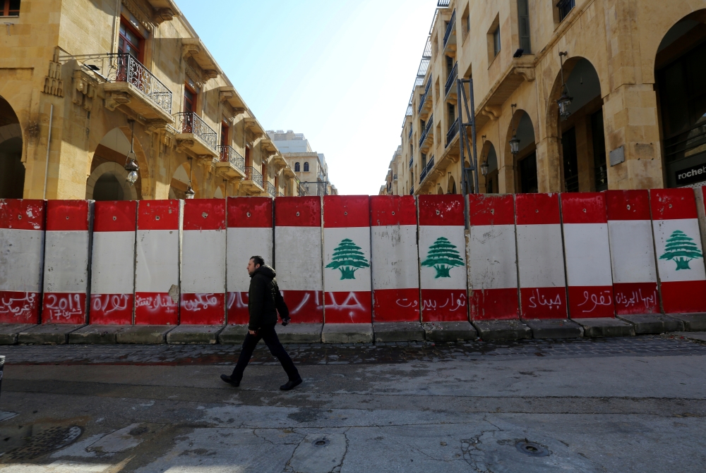 FILE PHOTO: A man walks past concrete barriers erected by authorities to block a street leading to the parliament building in Beirut, Lebanon January 24, 2020. REUTERS/Aziz Taher