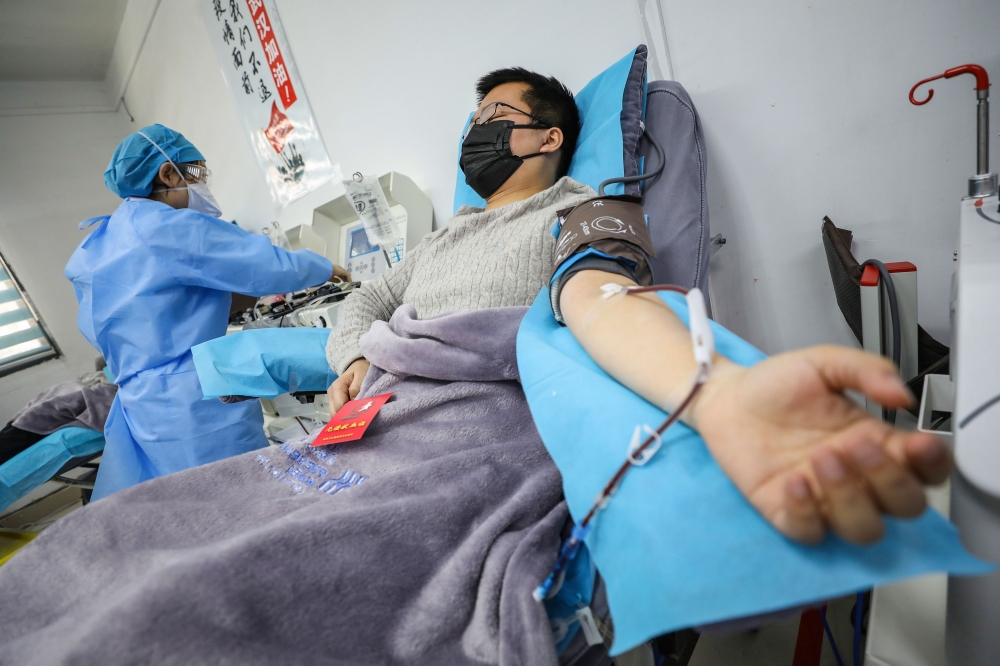 This photo taken on February 18, 2020 shows a doctor (R) who has recovered from the COVID-19 coronavirus infection donating plasma in Wuhan in China's central Hubei province. China OUT / AFP / STR