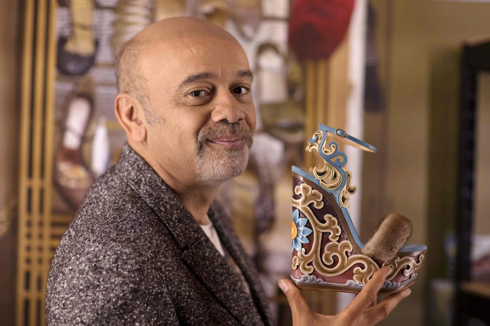 French shoe designer Christian Louboutin poses with one of his creations during a photo session at the Palais de la Porte Doree in Paris a few days before the opening of his exhibition 