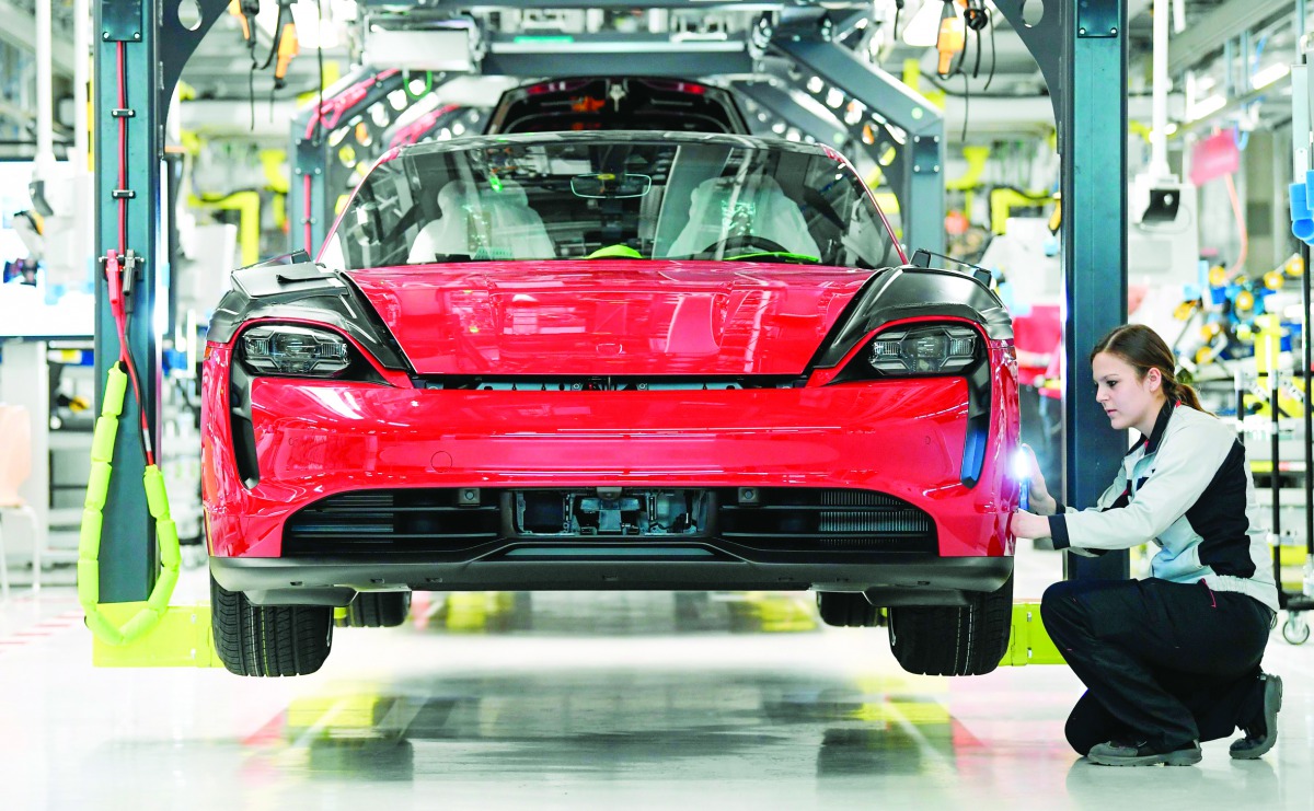 An employee of German luxury car maker Porsche AG works on a Porsche Taycan, Porsche's first all-electric powered car, on the assembly line in the company's plant in Stuttgart, southwestern Germany, on March 4, 2020. AFP / Thomas Kienzle
